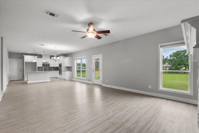 5000 Boreas Dr, Alvin, TX 77511 - unfurnished living room with ceiling fan, healthy amount of natural light, light wood-type flooring, and a chandelier