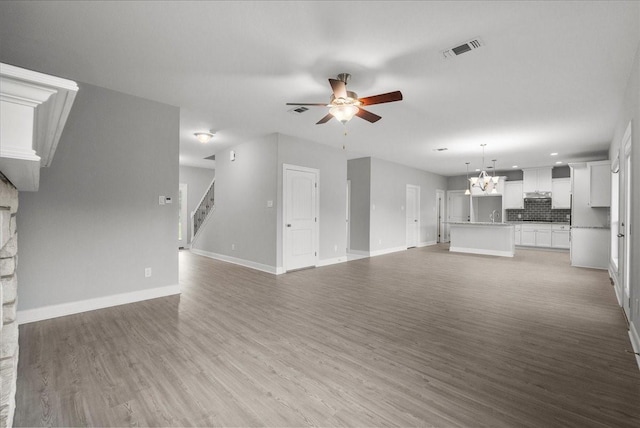 5000 Boreas Dr, Alvin, TX 77511 - unfurnished living room featuring ceiling fan, light wood-style flooring, a chandelier, stairway, and recessed lighting