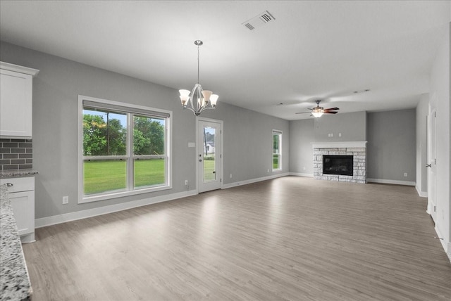 5000 Boreas Dr, Alvin, TX 77511 - unfurnished living room with a stone fireplace, light wood finished floors, a ceiling fan, and plenty of natural light