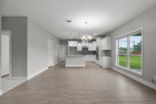 5000 Boreas Dr, Alvin, TX 77511 - kitchen with a chandelier, light wood-type flooring, backsplash, open floor plan, and white cabinets