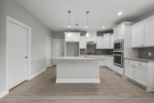 5000 Boreas Dr, Alvin, TX 77511 - kitchen with appliances with stainless steel finishes, backsplash, under cabinet range hood, white cabinetry, and a kitchen island with sink