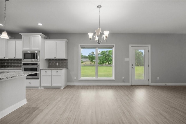 5000 Boreas Dr, Alvin, TX 77511 - kitchen with stainless steel appliances, light wood-style flooring, decorative backsplash, white cabinets, and a chandelier