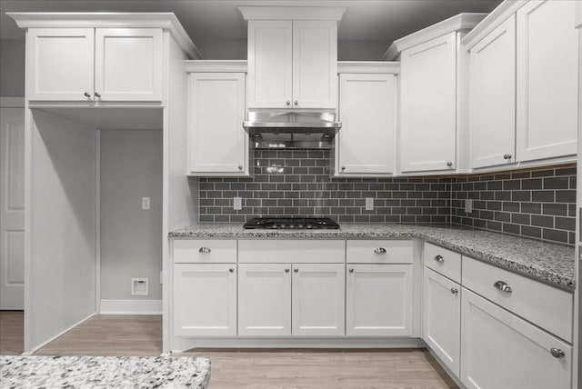 5000 Boreas Dr, Alvin, TX 77511 - kitchen with stainless steel gas cooktop, ventilation hood, light wood finished floors, decorative backsplash, and white cabinets