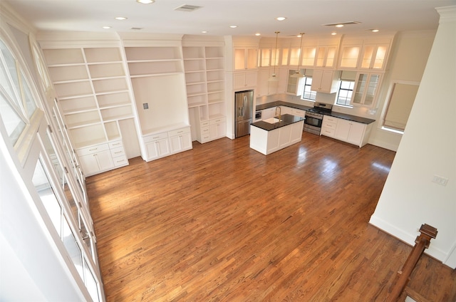 1605 Cohn St, Houston, TX 77007 - kitchen featuring dark countertops, a center island, appliances with stainless steel finishes, crown molding, and white cabinetry