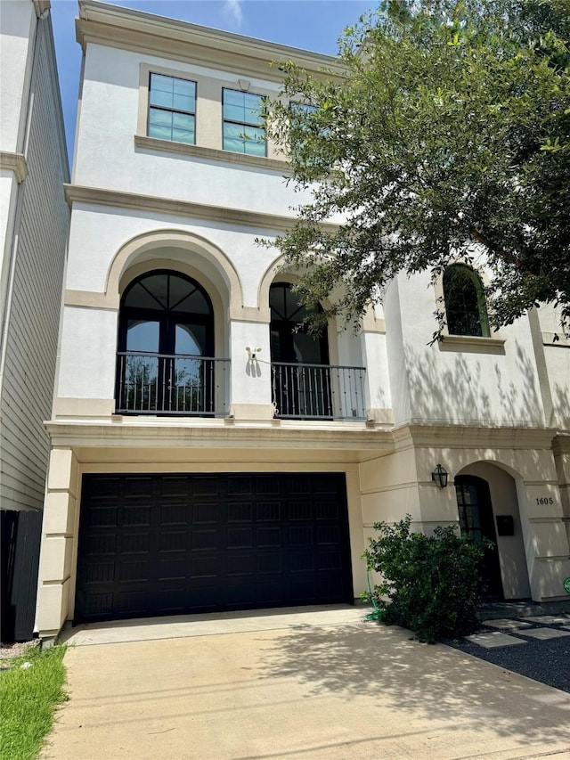 1605 Cohn St, Houston, TX 77007 - view of front facade featuring a garage, stucco siding, concrete driveway, and a balcony