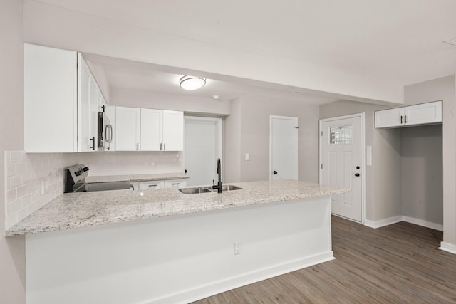 116 Harbour Ln, Coldspring, TX 77331 - kitchen with range with electric cooktop, stainless steel microwave, a peninsula, tasteful backsplash, and dark wood-type flooring
