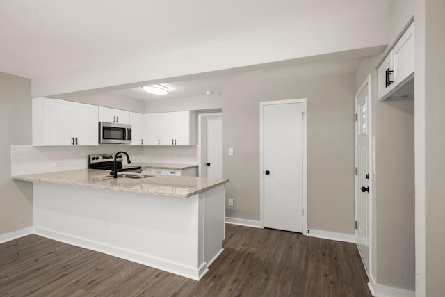 116 Harbour Ln, Coldspring, TX 77331 - kitchen featuring stainless steel microwave, a peninsula, dark wood finished floors, white cabinetry, and light stone countertops