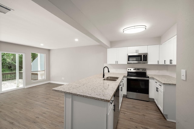 116 Harbour Ln, Coldspring, TX 77331 - kitchen featuring appliances with stainless steel finishes, wood finished floors, a peninsula, light stone countertops, and recessed lighting