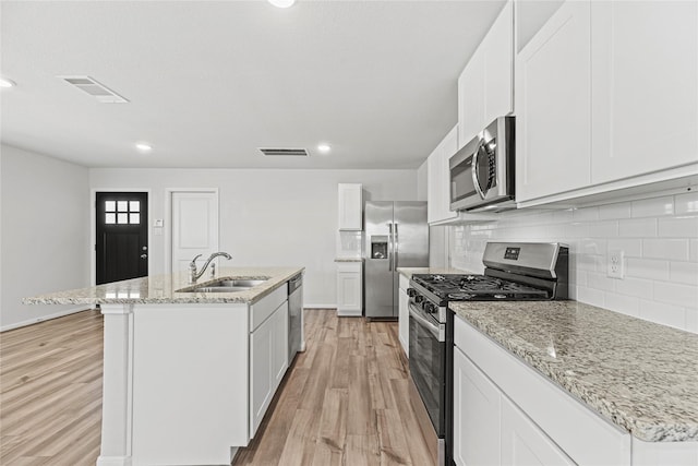 5263 Shallowhurst Ln, Katy, TX 77449 - kitchen with stainless steel appliances, light wood finished floors, a center island with sink, tasteful backsplash, and light stone countertops