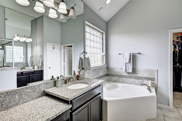 3854 Fleetwood Falls Ln, Spring, TX 77386 - bathroom featuring a bath, lofted ceiling, two vanities, and a spacious closet