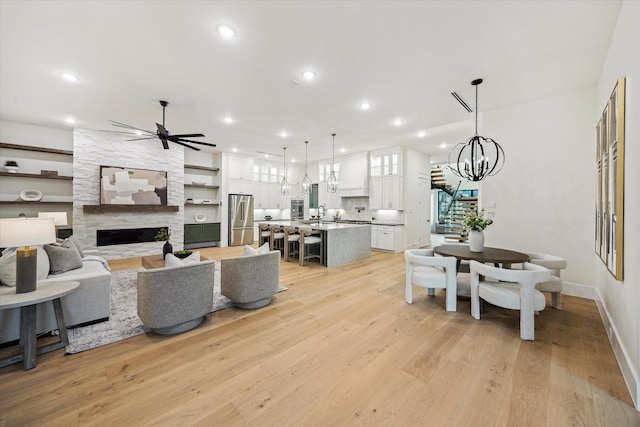 431 W 30th St, Houston, TX 77018 - living room with ceiling fan, light wood-style flooring, a stone fireplace, a chandelier, and recessed lighting