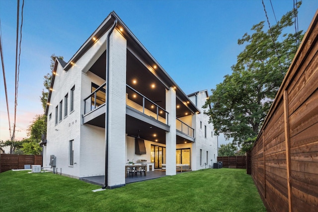 431 W 30th St, Houston, TX 77018 - back of property at dusk featuring a balcony, a fenced backyard, a patio area, and brick siding