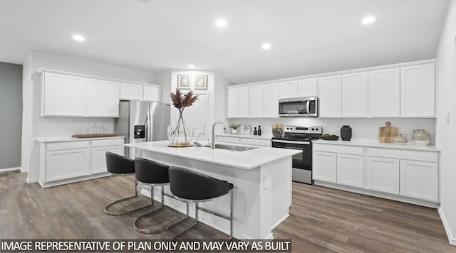 11123 Williams Reserve Dr, Conroe, TX 77303 - kitchen featuring appliances with stainless steel finishes, white cabinetry, wood finished floors, a kitchen island with sink, and light countertops