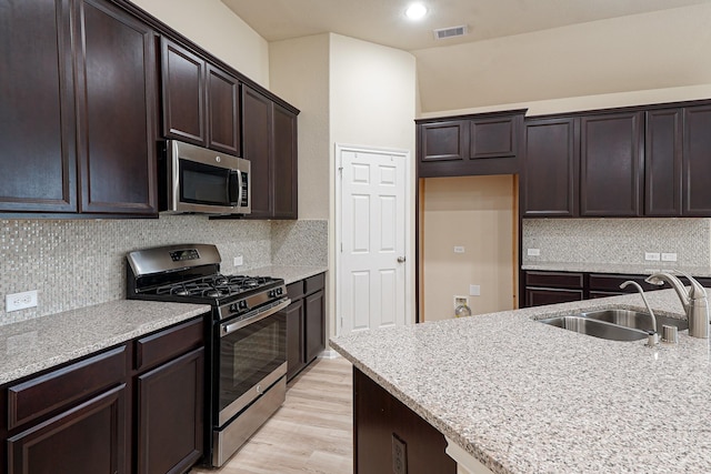 19022 Summer Farm Trl, Richmond, TX 77407 - kitchen with appliances with stainless steel finishes, light countertops, dark brown cabinets, light wood-style floors, and backsplash