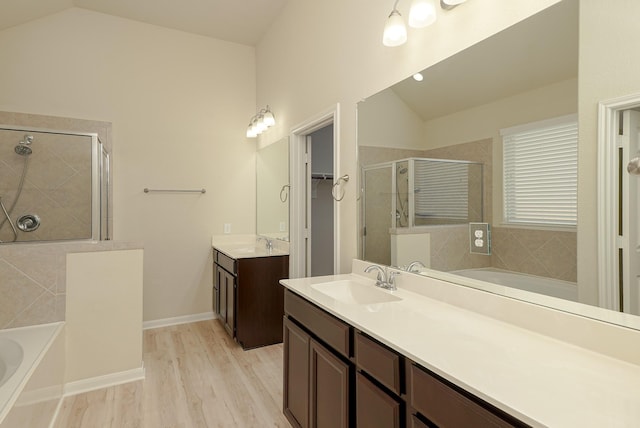 19022 Summer Farm Trl, Richmond, TX 77407 - full bathroom with lofted ceiling, a shower stall, a bath, two vanities, and wood finished floors
