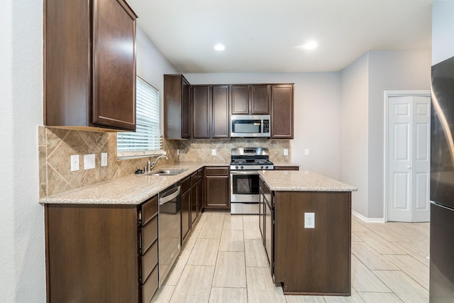 20027 Bayliss Manor Ln, Cypress, TX 77433 - kitchen featuring appliances with stainless steel finishes, a kitchen island, dark brown cabinetry, tasteful backsplash, and light stone counters