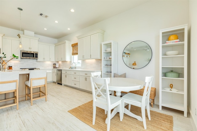2401 103rd St, Galveston, TX 77554 - kitchen with stainless steel appliances, light countertops, light wood-type flooring, tasteful backsplash, and recessed lighting