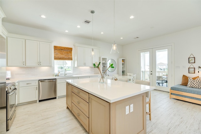 2401 103rd St, Galveston, TX 77554 - kitchen with appliances with stainless steel finishes, french doors, tasteful backsplash, a breakfast bar, and light wood-style floors