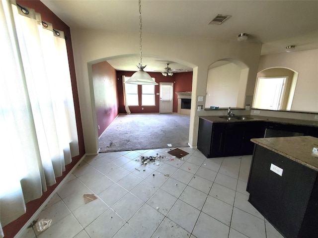 2714 Glenfield Manor Ln, Houston, TX 77014 - kitchen with a fireplace, arched walkways, light carpet, dark cabinets, and ceiling fan