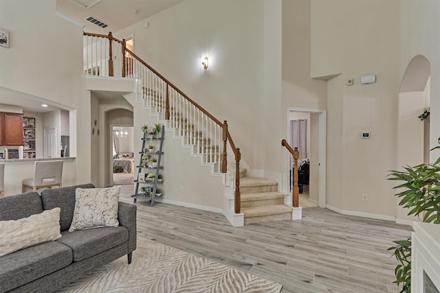 135 Forest Heights Way, Montgomery, TX 77316 - living room featuring arched walkways, a towering ceiling, light wood-style flooring, and stairway