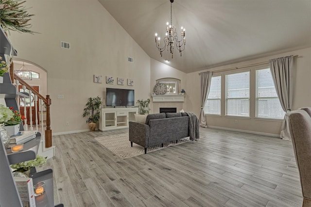 135 Forest Heights Way, Montgomery, TX 77316 - living room featuring a chandelier, light wood-style flooring, stairway, high vaulted ceiling, and a tiled fireplace