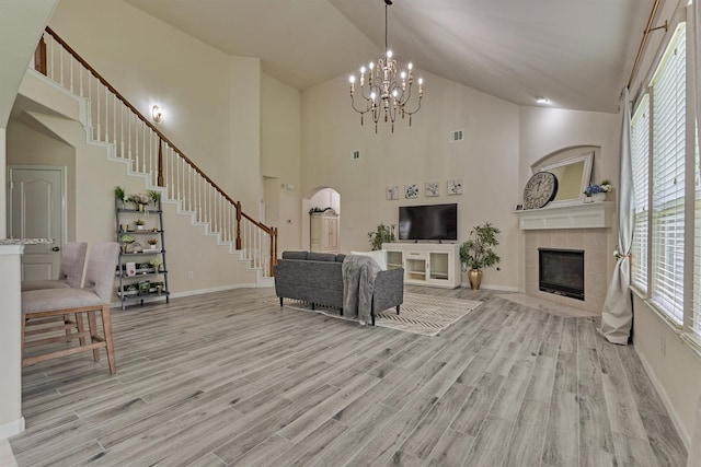 135 Forest Heights Way, Montgomery, TX 77316 - living room with stairway, high vaulted ceiling, light wood-style floors, a fireplace, and a chandelier