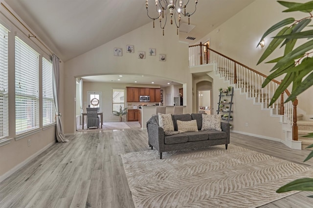 135 Forest Heights Way, Montgomery, TX 77316 - living room featuring arched walkways, high vaulted ceiling, light wood-type flooring, a chandelier, and stairway