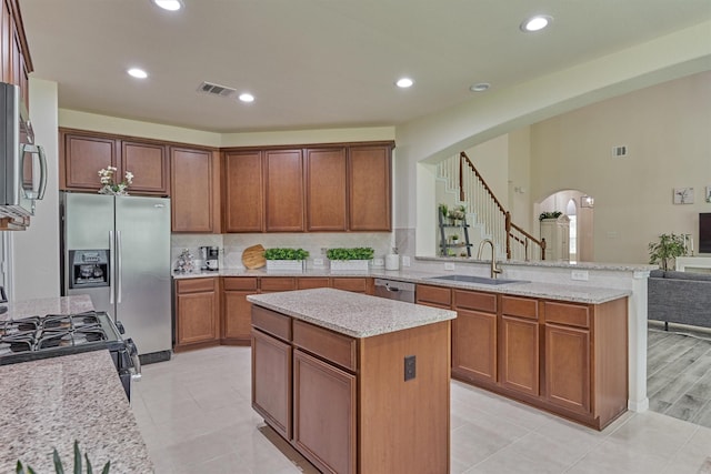 135 Forest Heights Way, Montgomery, TX 77316 - kitchen with arched walkways, stainless steel appliances, a peninsula, light stone counters, and a center island