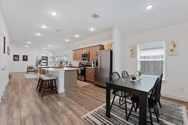 21635 Alberta Forest Cir, Magnolia, TX 77355 - kitchen with appliances with stainless steel finishes, a center island, a kitchen bar, light countertops, and light wood-style flooring