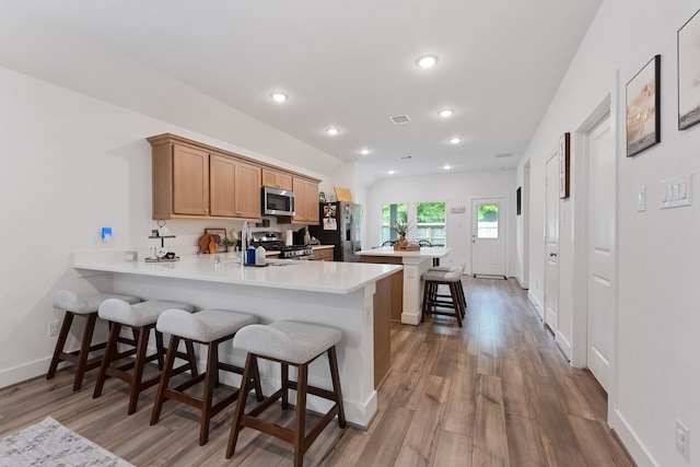 21635 Alberta Forest Cir, Magnolia, TX 77355 - kitchen with appliances with stainless steel finishes, a kitchen breakfast bar, light wood-type flooring, light countertops, and recessed lighting