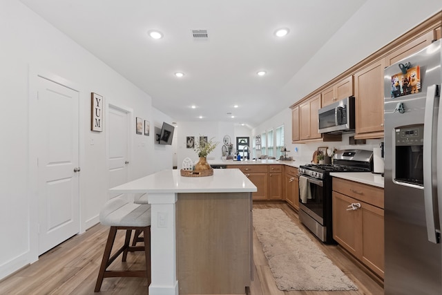 21635 Alberta Forest Cir, Magnolia, TX 77355 - kitchen with appliances with stainless steel finishes, light wood-style floors, a breakfast bar area, light countertops, and a peninsula
