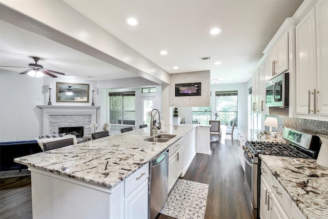 18415 Pin Oak Bend Dr, Cypress, TX 77433 - kitchen with stainless steel appliances, a fireplace, ceiling fan, white cabinets, and open floor plan