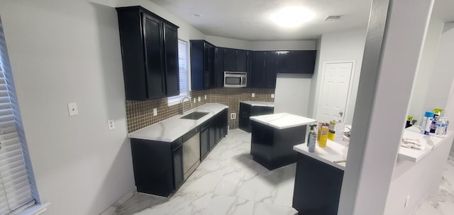 71 N Forrest Ave, La Porte, TX 77571 - kitchen featuring dark cabinets, stainless steel microwave, light marble finish flooring, tasteful backsplash, and light countertops