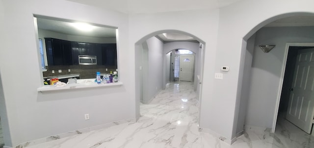 71 N Forrest Ave, La Porte, TX 77571 - kitchen featuring stainless steel microwave, dark cabinets, light marble finish flooring, and arched walkways