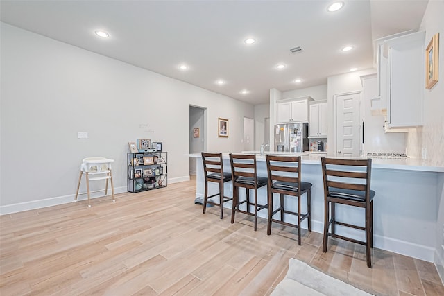 7522 Zion Grove Ct, Katy, TX 77493 - kitchen featuring stainless steel fridge, white cabinetry, a kitchen breakfast bar, light countertops, and a peninsula