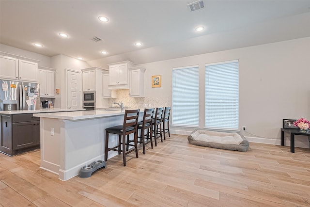 7522 Zion Grove Ct, Katy, TX 77493 - kitchen with light wood-style flooring, stainless steel appliances, a peninsula, light countertops, and a kitchen bar