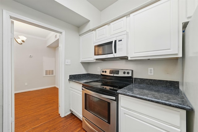 2255 Braeswood Park Dr Unit 181, Houston, TX 77030 - kitchen with stainless steel electric range oven, white microwave, crown molding, dark wood-type flooring, and dark countertops