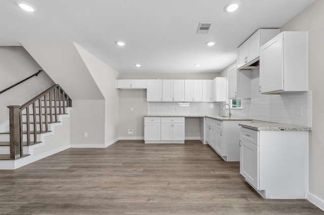 6313 Sandra St, Houston, TX 77028 - kitchen featuring backsplash, light wood-style flooring, white cabinetry, recessed lighting, and light stone countertops