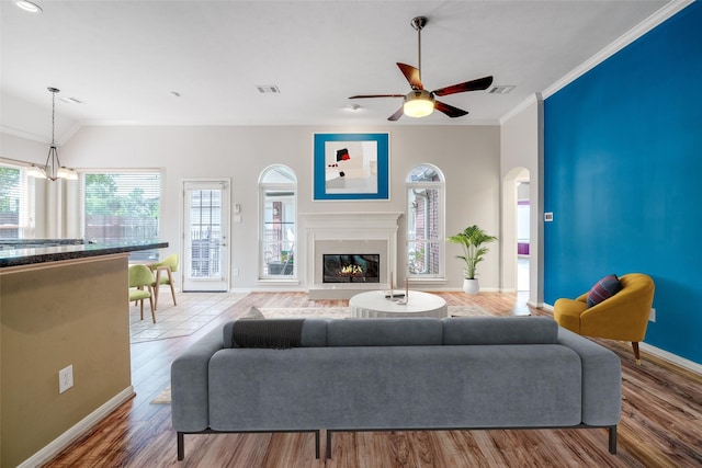 7422 Quiet Glen Dr, Sugar Land, TX 77479 - living area with crown molding, wood finished floors, arched walkways, a glass covered fireplace, and a ceiling fan