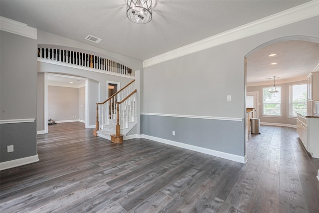 9526 Fern Wood Frst, Houston, TX 77040 - spare room with arched walkways, dark wood-type flooring, ornamental molding, stairway, and a chandelier