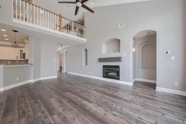 9526 Fern Wood Frst, Houston, TX 77040 - unfurnished living room with ceiling fan, a glass covered fireplace, wood finished floors, crown molding, and high vaulted ceiling