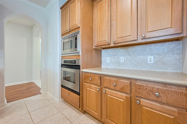 7927 Chateau Point Ln, Houston, TX 77041 - kitchen featuring appliances with stainless steel finishes, arched walkways, decorative backsplash, ornamental molding, and light tile patterned floors