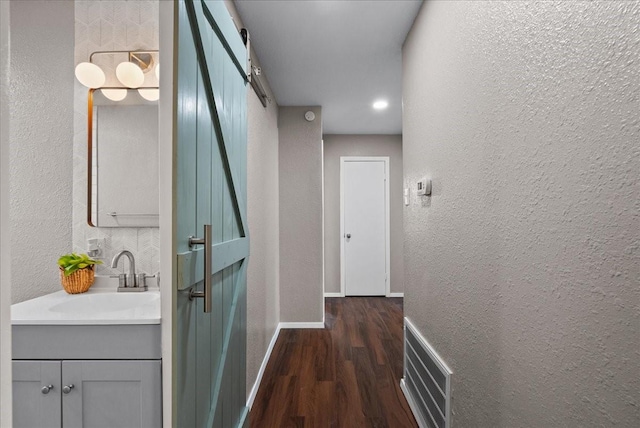 2909 15th Ave N, Texas City, TX 77590 - hallway featuring a textured wall, a barn door, and dark wood-style flooring