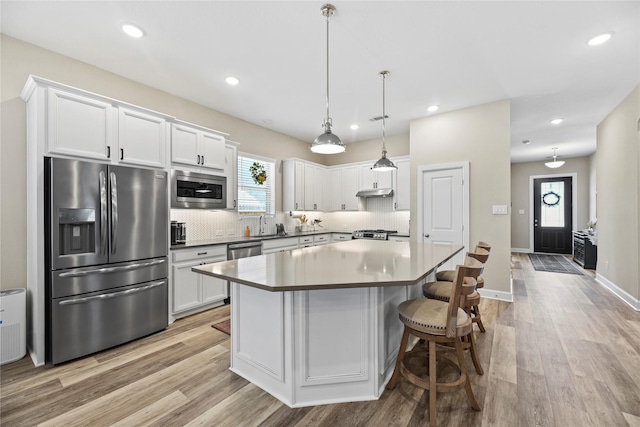11819 Dockside Shores Dr, Cypress, TX 77433 - kitchen featuring stainless steel appliances, white cabinets, tasteful backsplash, a kitchen island, and light wood-style floors