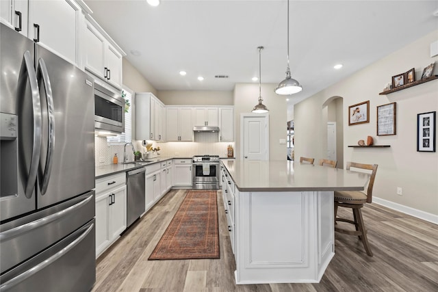 11819 Dockside Shores Dr, Cypress, TX 77433 - kitchen with appliances with stainless steel finishes, arched walkways, light wood-style flooring, white cabinetry, and recessed lighting