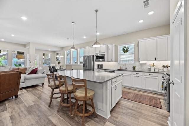 11819 Dockside Shores Dr, Cypress, TX 77433 - kitchen with appliances with stainless steel finishes, open floor plan, white cabinets, a kitchen island, and decorative backsplash