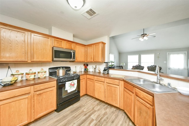 14503 Brackenhurst Ln, Houston, TX 77049 - kitchen with stainless steel microwave, black gas stove, light wood-type flooring, a ceiling fan, and vaulted ceiling