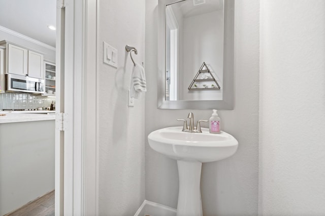 1509 Grayson Oaks Pl, Houston, TX 77043 - bathroom featuring crown molding, decorative backsplash, and wood finished floors