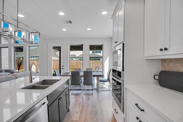 18702 Denio Site Dr, Cypress, TX 77433 - kitchen with stainless steel appliances, backsplash, light wood finished floors, recessed lighting, and light countertops