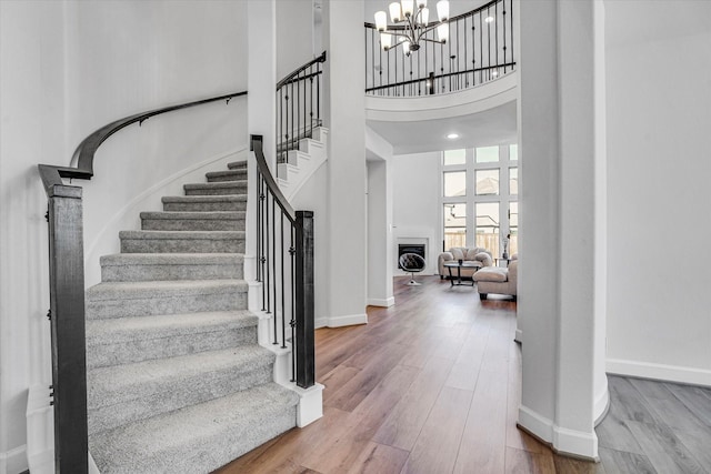 18702 Denio Site Dr, Cypress, TX 77433 - stairway with a chandelier, wood finished floors, a high ceiling, and a fireplace
